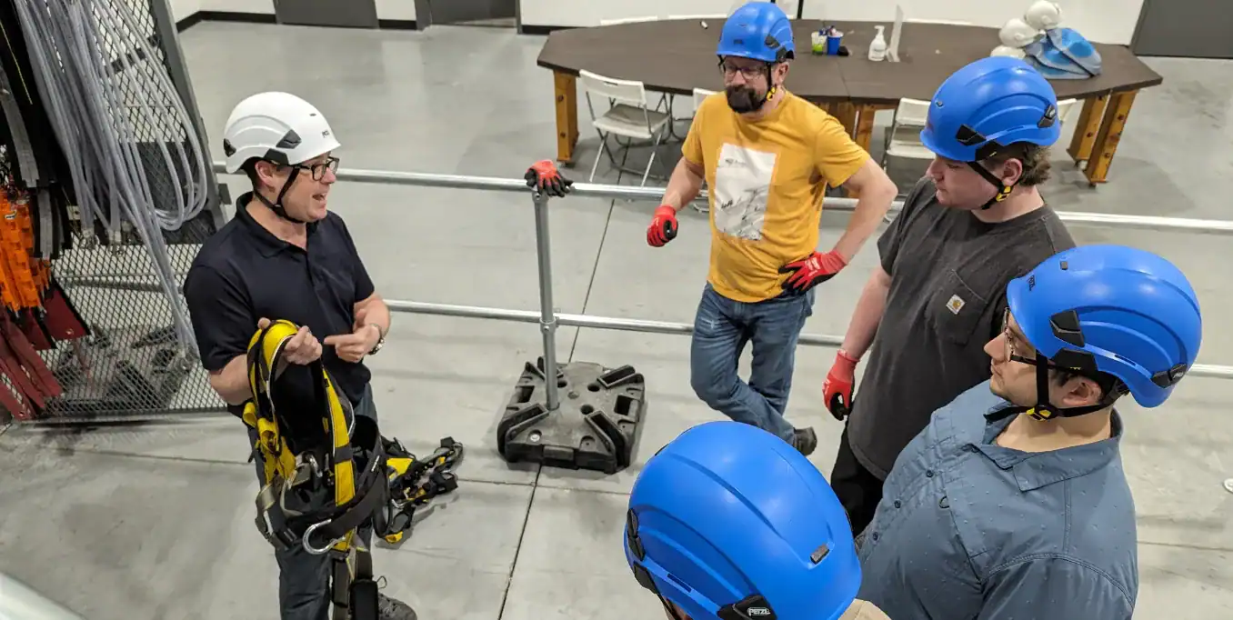 Instructor demonstrating fall protection harness to students during PFPE training.